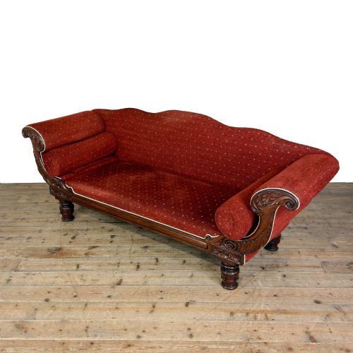 fig 1. An antique Victorian walnut sofa with carved scroll arms, red patterned fabric upholstery, bolster cushions, and turned legs.