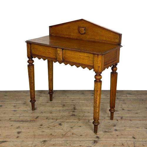 fig 1. An antique warm brown oak hall table featuring a triangular gallery back with a central carved shield motif, a scalloped apron, and turned legs.