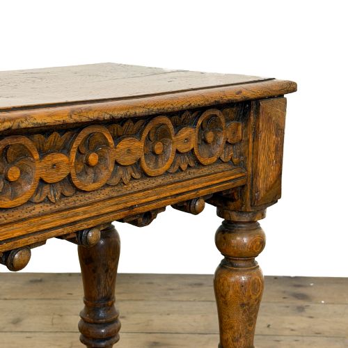 fig 1. A long Victorian carved oak hall bench featuring a detailed floral rosette frieze, acorn drop pendants, and four turned legs on a light timber floor.