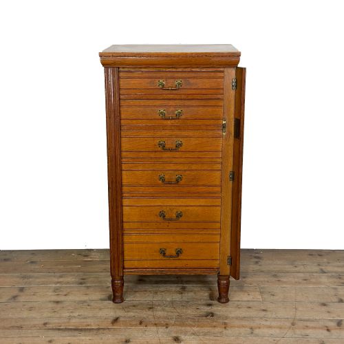 fig 1. A tall late Victorian oak Wellington chest featuring seven drawers with brass drop handles, fluted side pilasters, and turned feet.