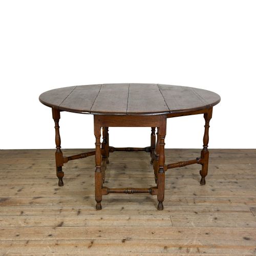 fig 1. A warm brown oak gateleg dining table with raised drop leaves, turned leg supports, and lower box stretchers.