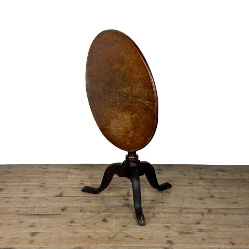 fig 1. A Georgian oak tilt top table with a circular top locked upright above a turned column pedestal and three shaped tripod legs.