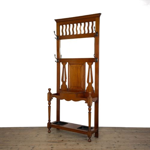 fig 1. An antique Edwardian oak hall stand featuring a central mirror, hanging hooks, vertical spindle detailing, and a lower umbrella rack with drip trays.