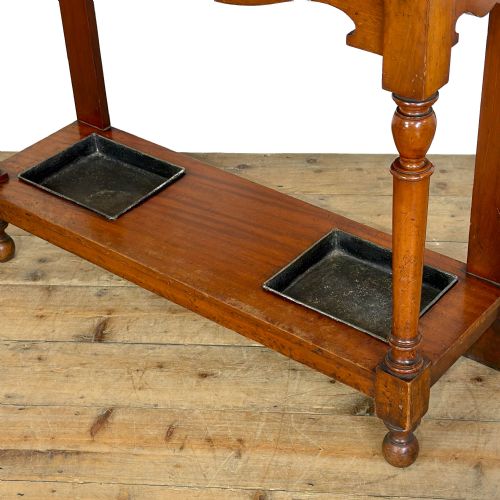 fig 2. An antique Edwardian oak hall stand featuring a central mirror, hanging hooks, vertical spindle detailing, and a lower umbrella rack with drip trays.