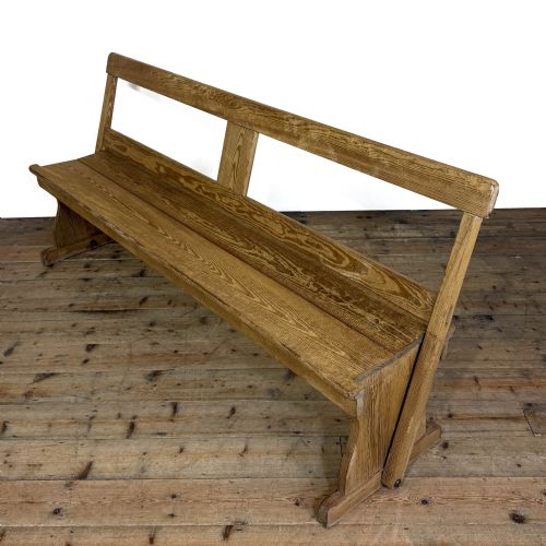 fig 2. A long pine chapel bench featuring a reversible flip-over backrest and solid wooden side supports on a timber floor.