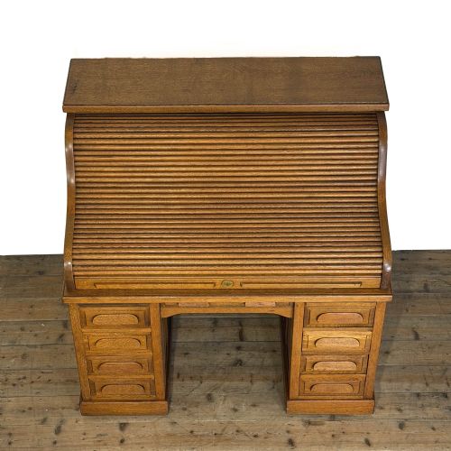 fig 1. An antique golden oak roll-top desk with twin pedestals, multiple drawers, and wooden cup handles.