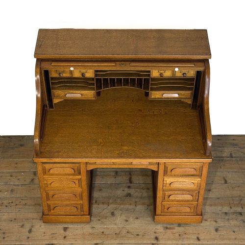 fig 2. An antique golden oak roll-top desk with twin pedestals, multiple drawers, and wooden cup handles.
