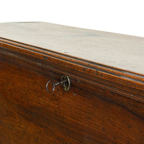 fig 1. A rectangular dark brown elm six-plank coffer featuring a hinged lid, keyhole escutcheon, and cut-out shaped feet.