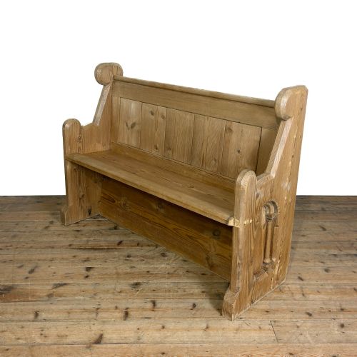 fig 1. A freestanding antique pine chapel pew featuring a panelled backrest, solid bench seat, and carved upright side supports.