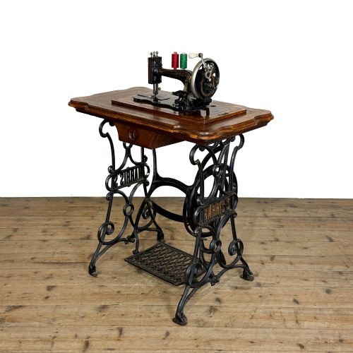 fig 1. An antique Harris treadle sewing machine with a domed wooden case resting on an ornamental black cast iron treadle base.