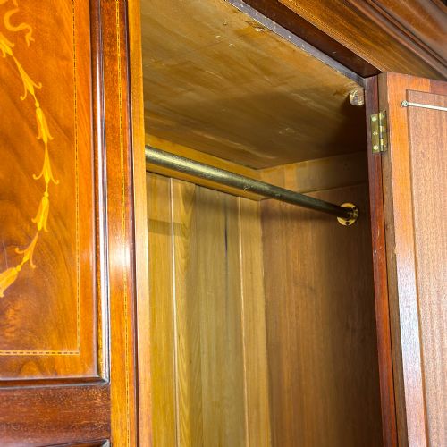 fig 2. An Edwardian mahogany three-door wardrobe with a central oval bevelled mirror, delicate satinwood marquetry panels, and two lower drawers.
