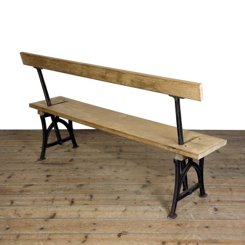 fig 1. An antique pine bench featuring a reversible backrest supported on dark cast iron legs.