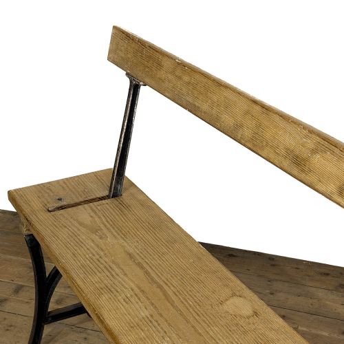 fig 2. An antique pine bench featuring a reversible backrest supported on dark cast iron legs.