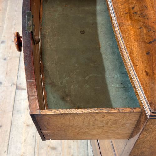 fig 1. An antique Regency period mahogany bow-front chest of drawers featuring two short over three long graduated drawers with turned wooden handles.