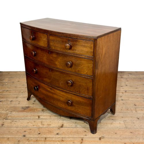 fig 2. An antique Regency period mahogany bow-front chest of drawers featuring two short over three long graduated drawers with turned wooden handles.