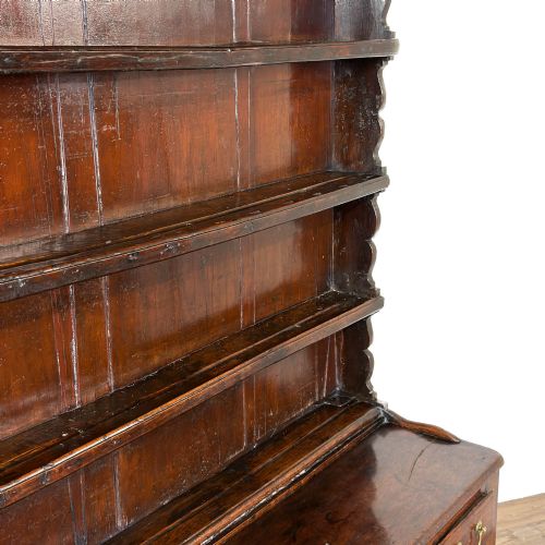 fig 2. An eighteenth-century dark oak Welsh dresser featuring an open three-tier plate rack with a scalloped top frieze over a three-drawer base with brass handles and a lower potboard shelf.