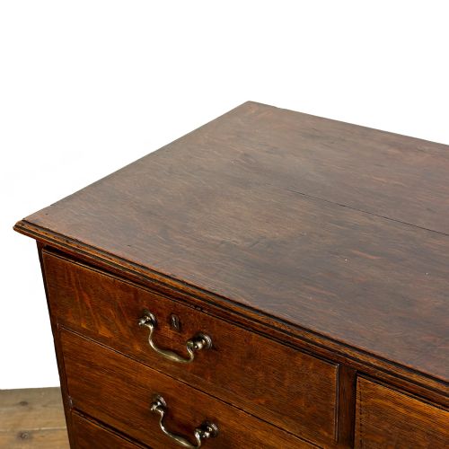 fig 1. A Georgian oak chest of drawers featuring two short over three long graduated drawers, brass swan-neck handles, keyhole escutcheons, and bracket feet.