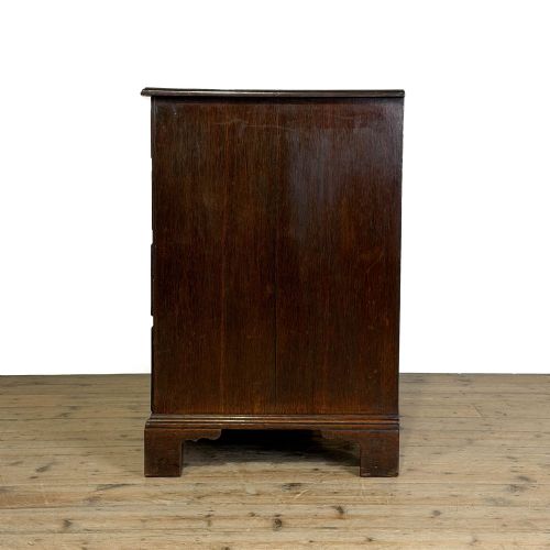 fig 2. A Georgian oak chest of drawers featuring two short over three long graduated drawers, brass swan-neck handles, keyhole escutcheons, and bracket feet.