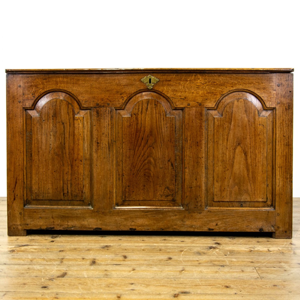 An eighteenth-century Welsh oak coffer featuring three arched raised front panels and a central brass keyhole escutcheon.