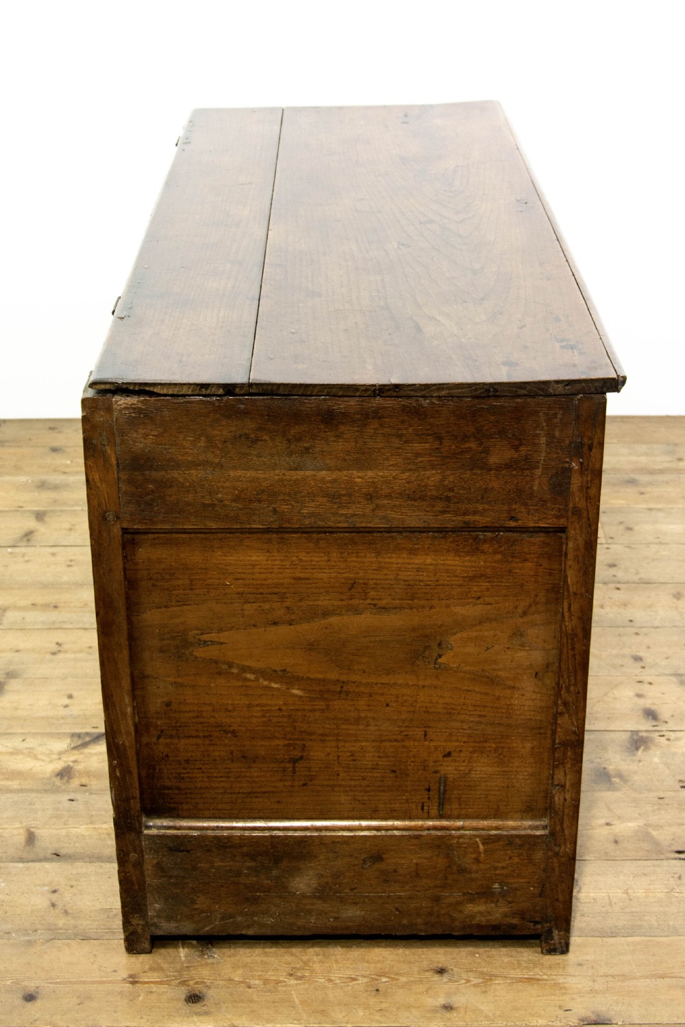 An eighteenth-century Welsh oak coffer featuring three arched raised front panels and a central brass keyhole escutcheon. View VI