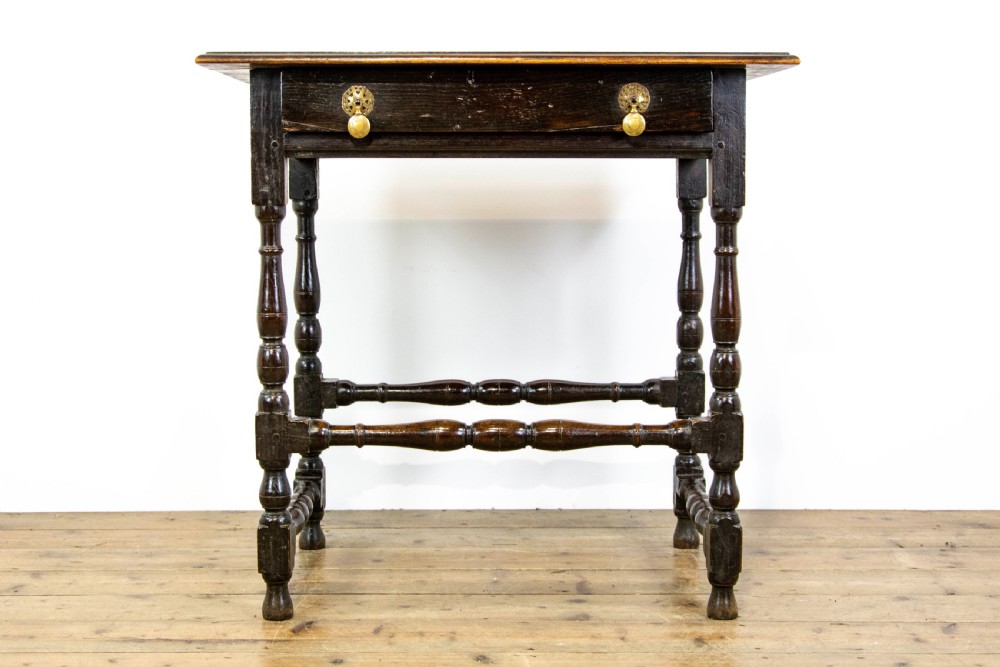 A dark elm side table featuring turned legs, horizontal turned stretchers, and a single drawer with brass drop handles. View II