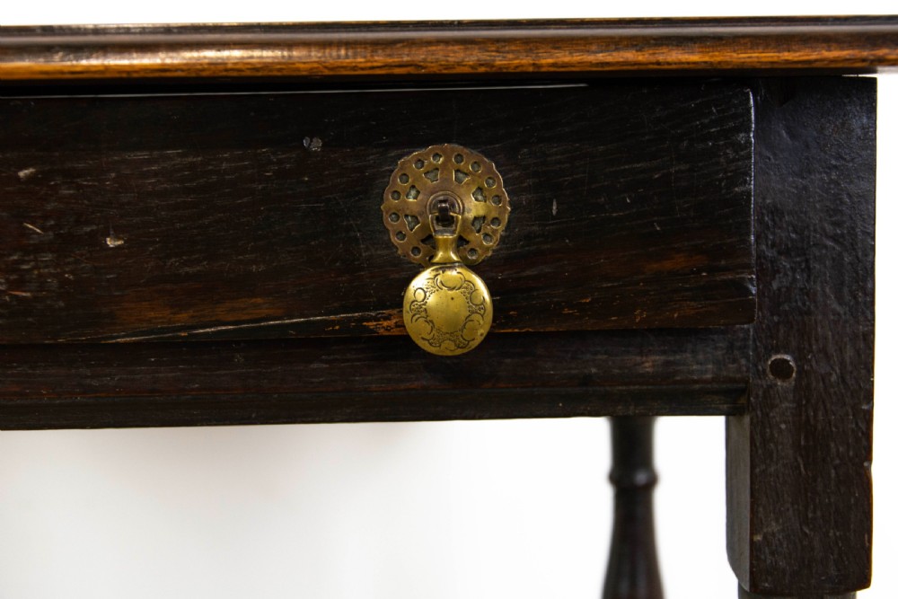A dark elm side table featuring turned legs, horizontal turned stretchers, and a single drawer with brass drop handles. View III