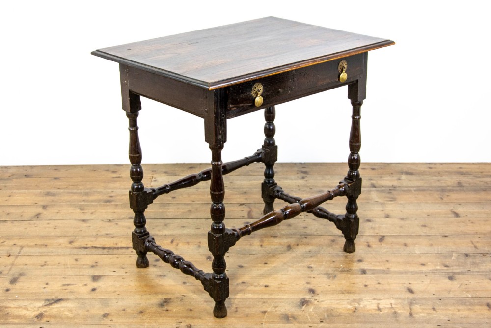A dark elm side table featuring turned legs, horizontal turned stretchers, and a single drawer with brass drop handles. View VI