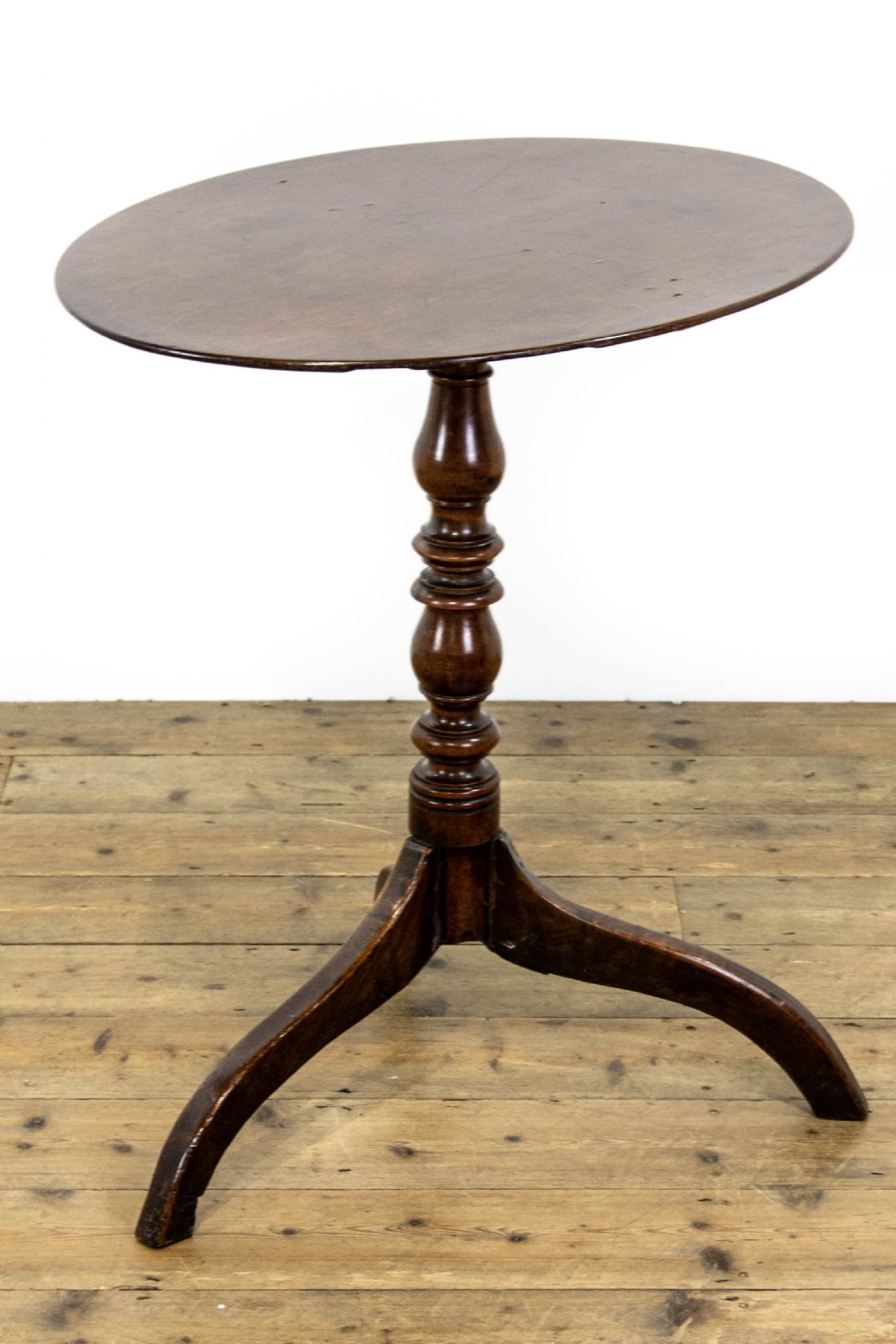 An antique mahogany side table featuring an oval top supported by a turned central pedestal and three curved tripod legs. View V