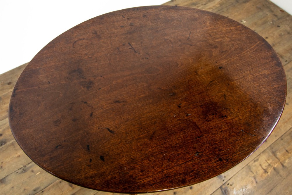 An antique mahogany side table featuring an oval top supported by a turned central pedestal and three curved tripod legs. View VII
