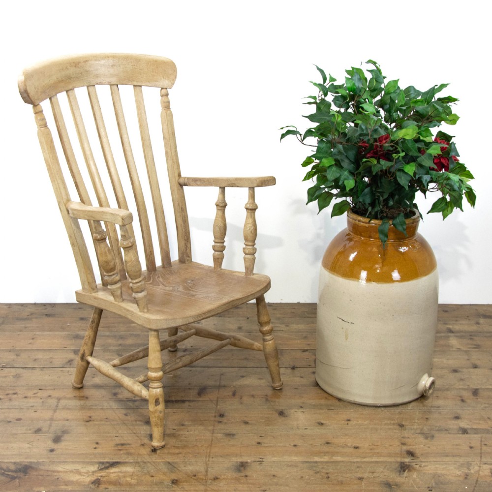 A light ash and elm antique Windsor armchair featuring a spindle backrest, turned legs, and a solid shaped wooden seat.