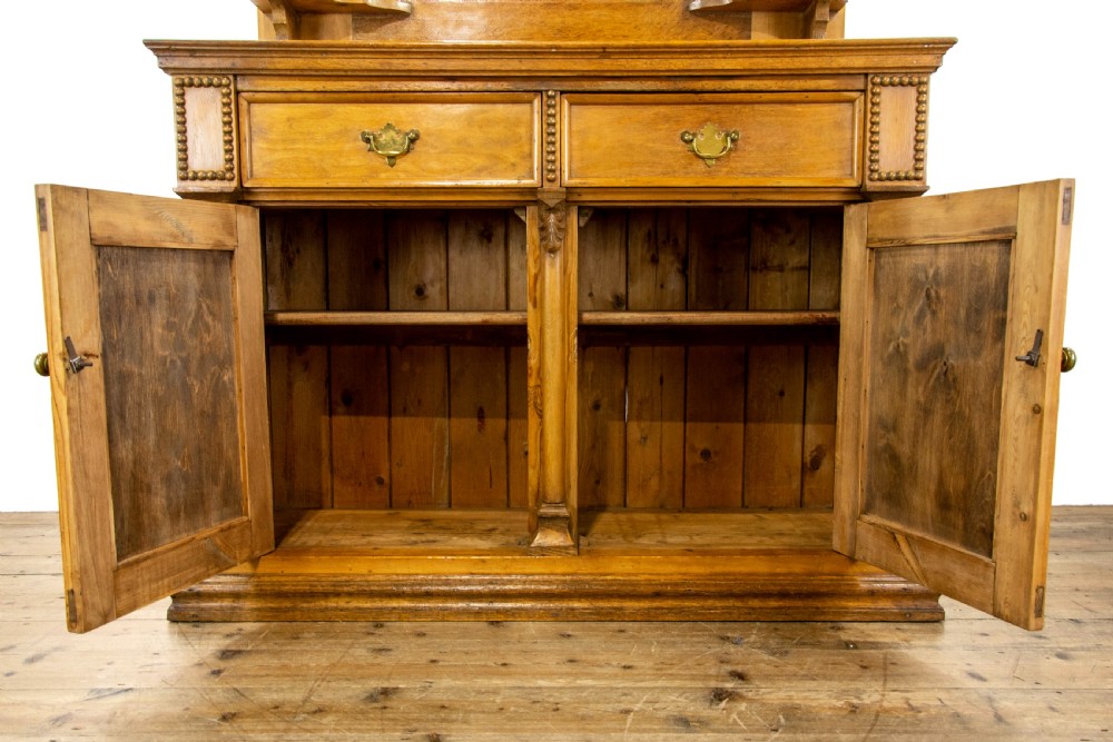 A light oak and pine sideboard featuring a raised mirror back with turned columns, two upper drawers, and a two-door lower cupboard. View V