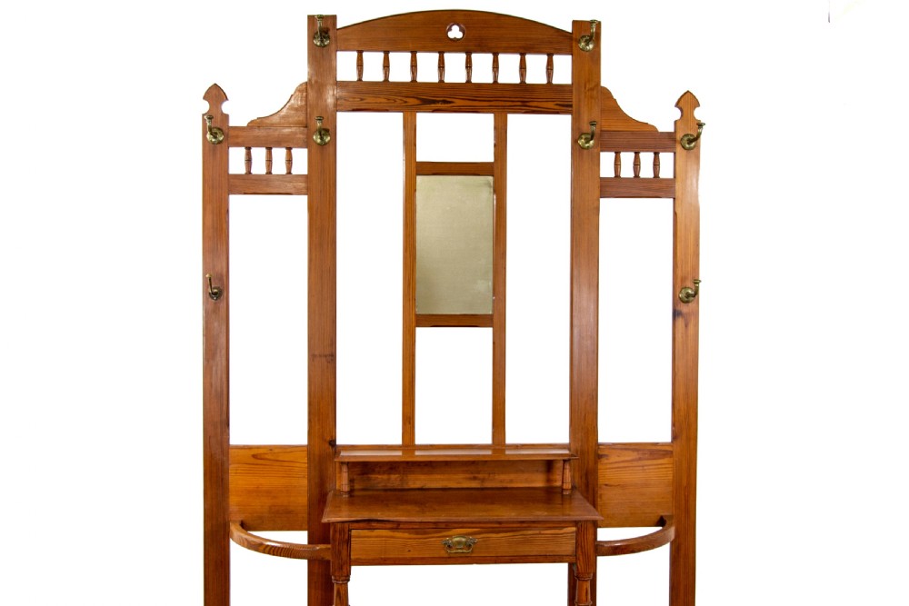 A tall Victorian pitch pine hall stand featuring a central mirror, brass coat hooks, a small drawer unit, and integrated umbrella racks with drip trays. View II
