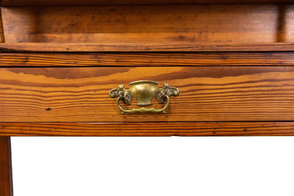 A tall Victorian pitch pine hall stand featuring a central mirror, brass coat hooks, a small drawer unit, and integrated umbrella racks with drip trays. View IV