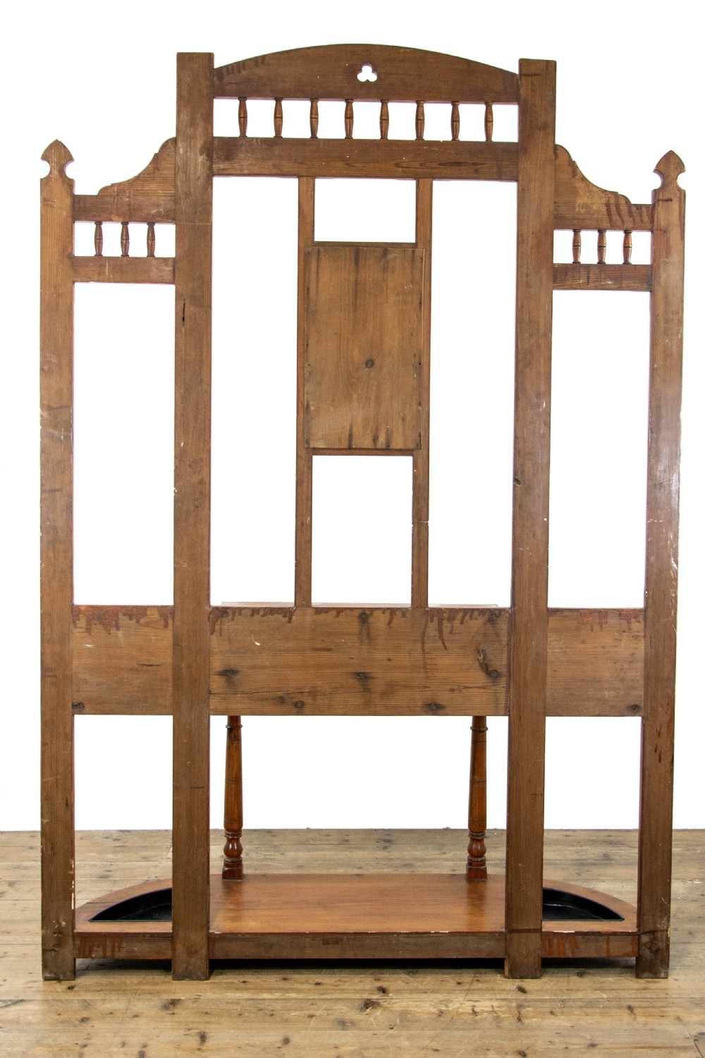A tall Victorian pitch pine hall stand featuring a central mirror, brass coat hooks, a small drawer unit, and integrated umbrella racks with drip trays. View XII