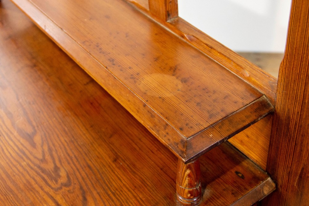 A tall Victorian pitch pine hall stand featuring a central mirror, brass coat hooks, a small drawer unit, and integrated umbrella racks with drip trays. View XIV