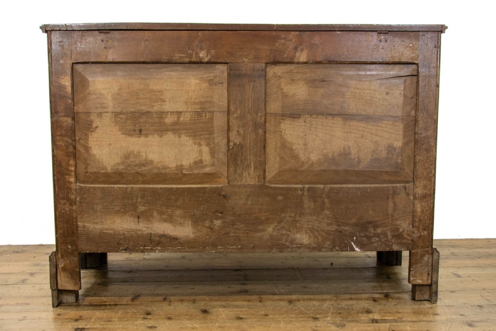 An antique dark oak mule chest featuring three recessed front panels, two lower drawers with brass swan-neck handles, and bracket feet. View VII