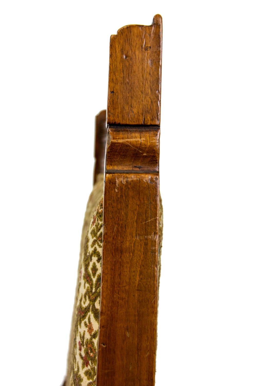 An antique Edwardian low-slung chair featuring a carved timber frame, patterned textile upholstery, turned front legs, and castors. View VIII