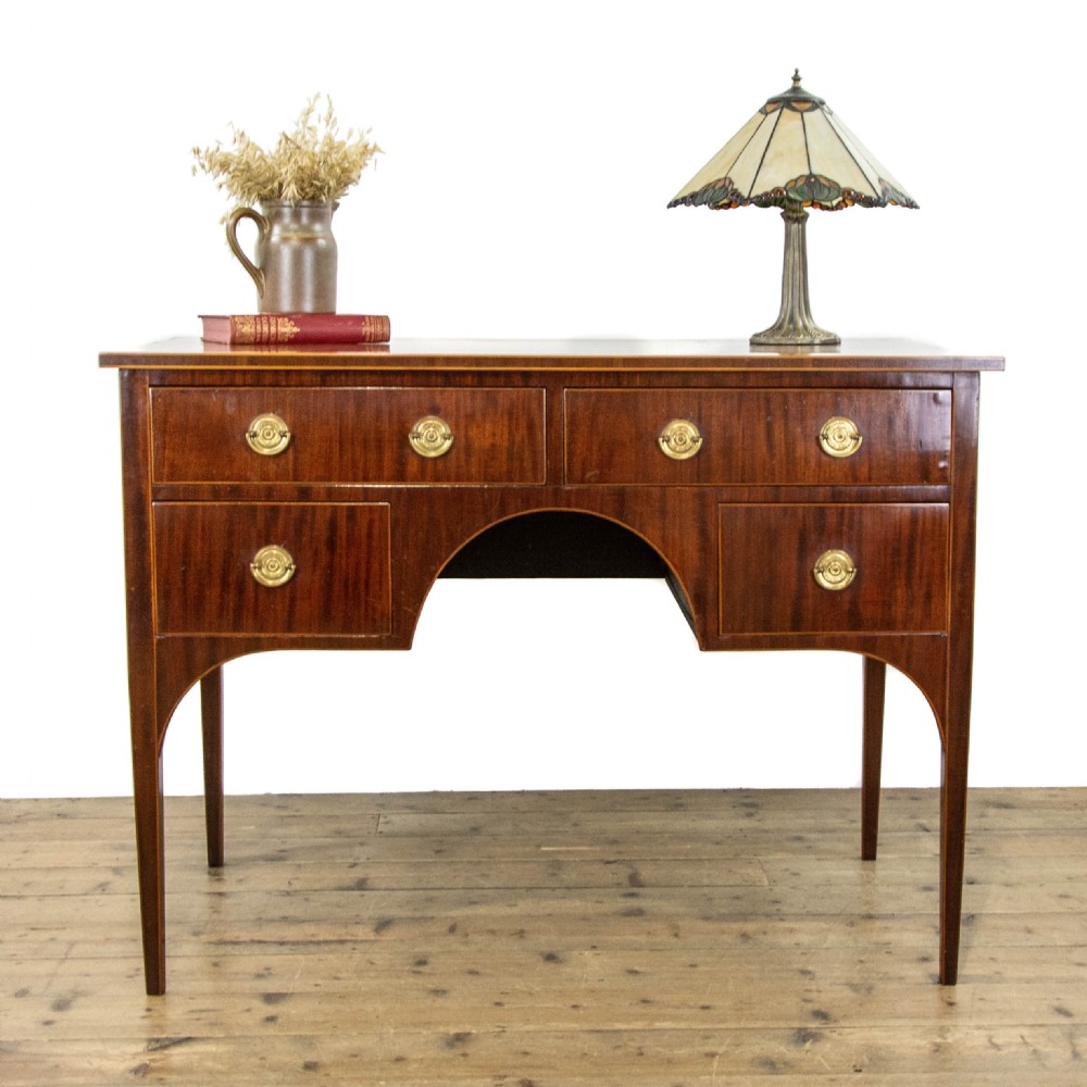 An antique Sheraton Revival mahogany side table featuring four drawers, string inlay detailing, brass ring handles, and an arched central kneehole on tapered square legs. View II