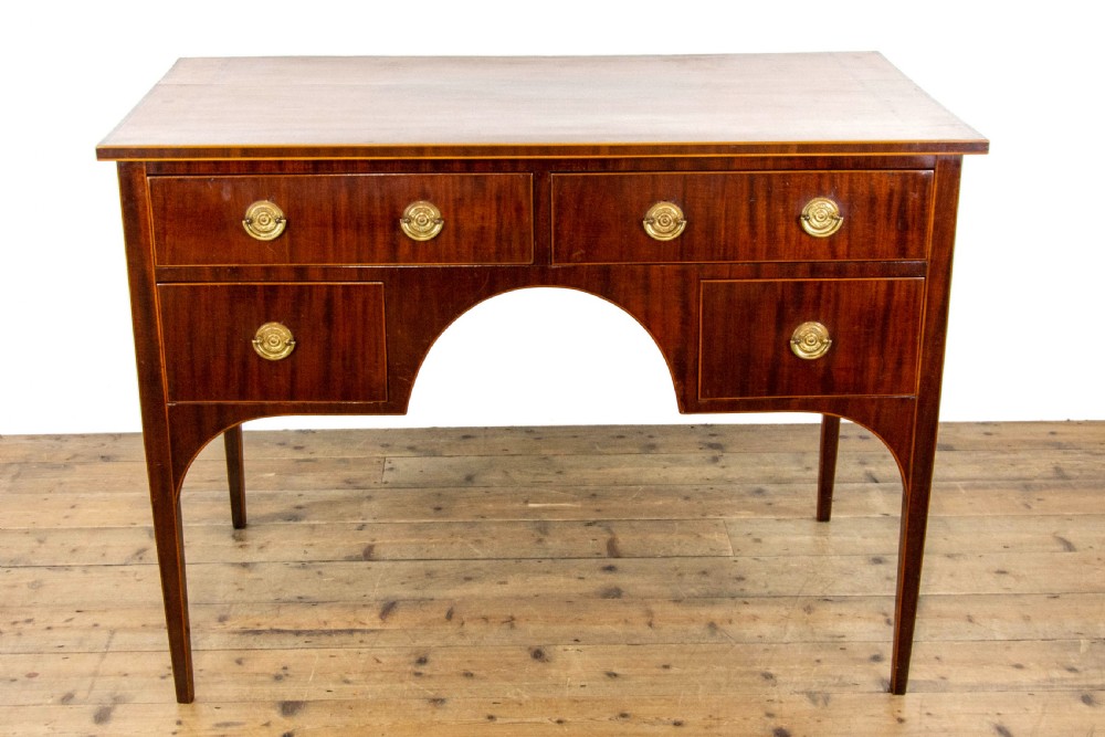 An antique Sheraton Revival mahogany side table featuring four drawers, string inlay detailing, brass ring handles, and an arched central kneehole on tapered square legs. View III