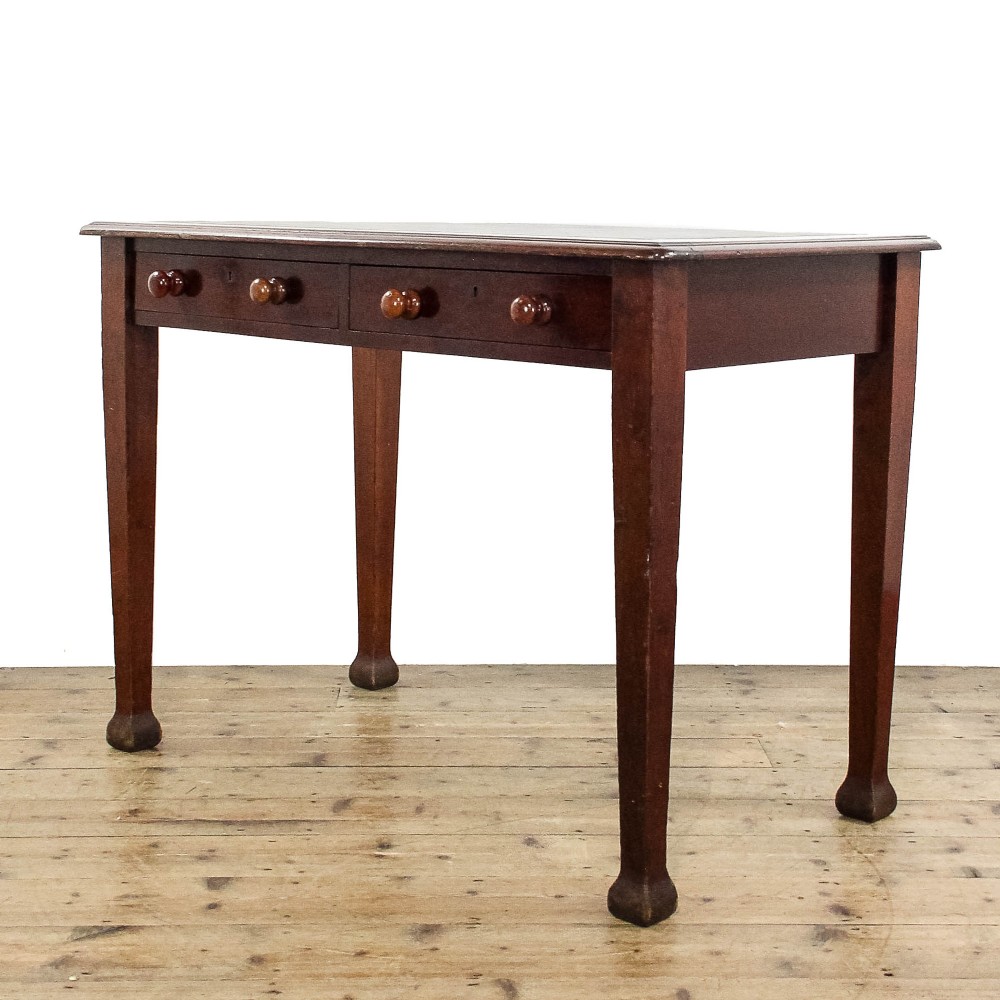 An antique Edwardian mahogany writing desk featuring two drawers with wooden knob handles and four square tapered legs.