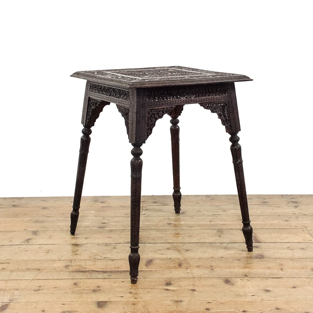A square dark wood side table featuring intricate foliate hand carving across the top, pierced decorative aprons, and turned legs.