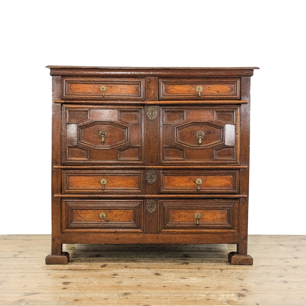 An 18th-century walnut chest of drawers featuring geometric moulded drawer fronts, string inlay, and decorative brass teardrop handles.
