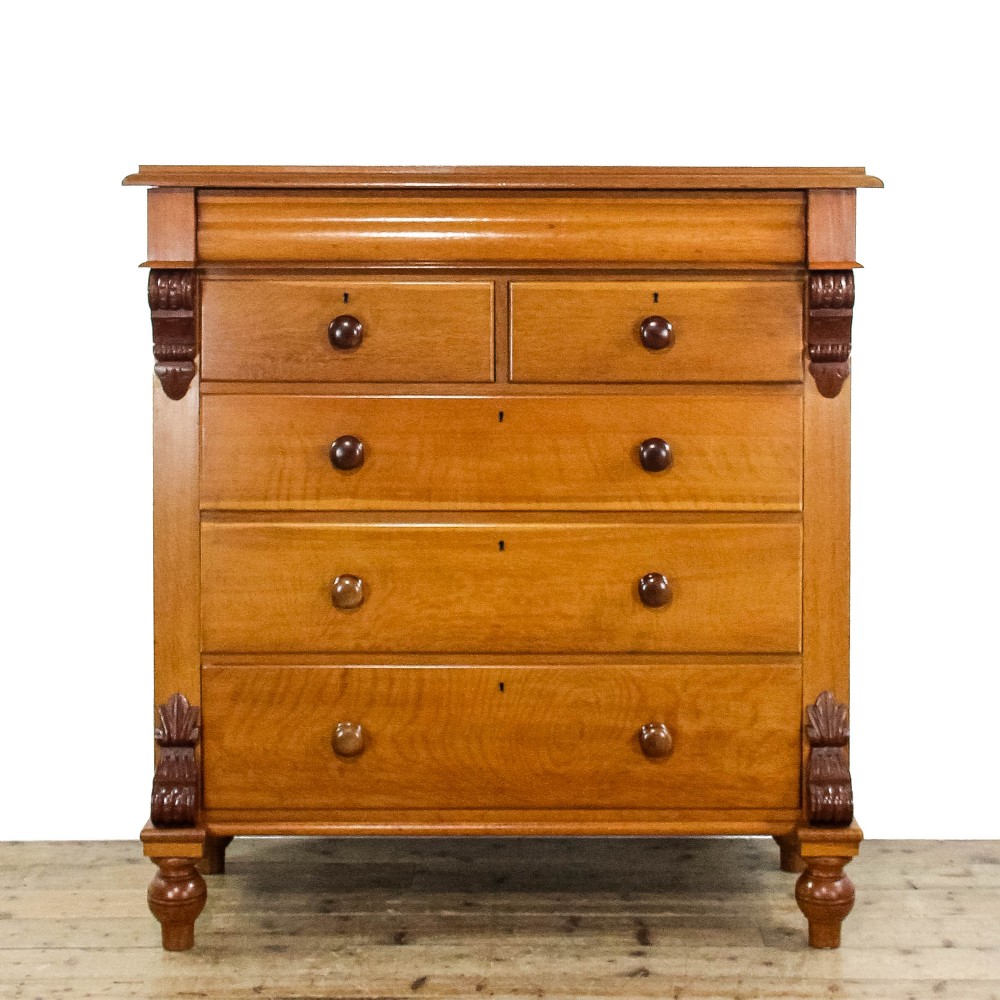 A Victorian oak straight-front chest of drawers featuring turned wooden knobs, carved side corbels, and turned feet.