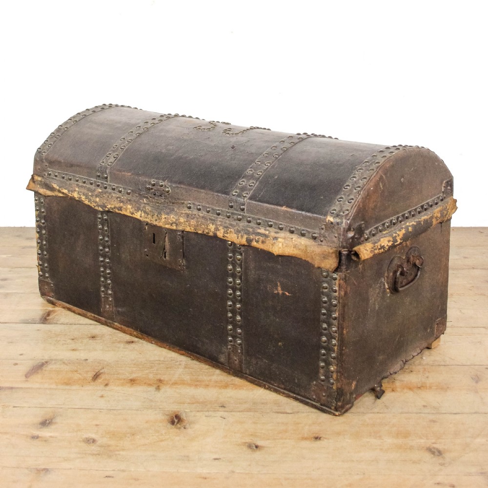 An antique dark brown leather domed trunk decorated with metal studs and initials on the curved lid. View II