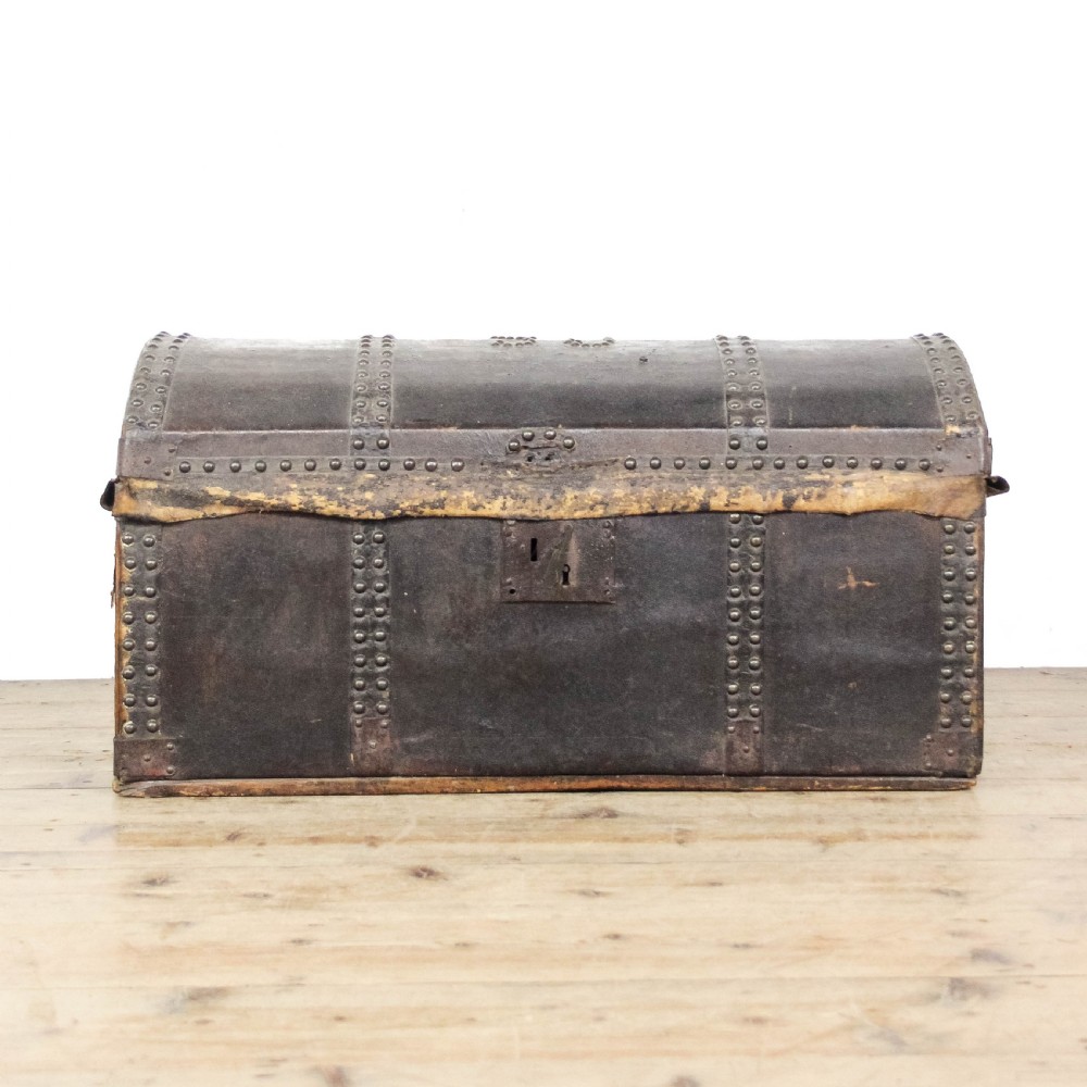 An antique dark brown leather domed trunk decorated with metal studs and initials on the curved lid. View V