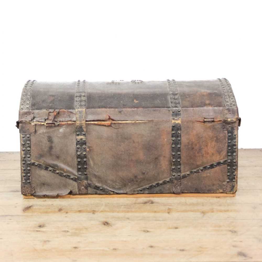 An antique dark brown leather domed trunk decorated with metal studs and initials on the curved lid. View VI
