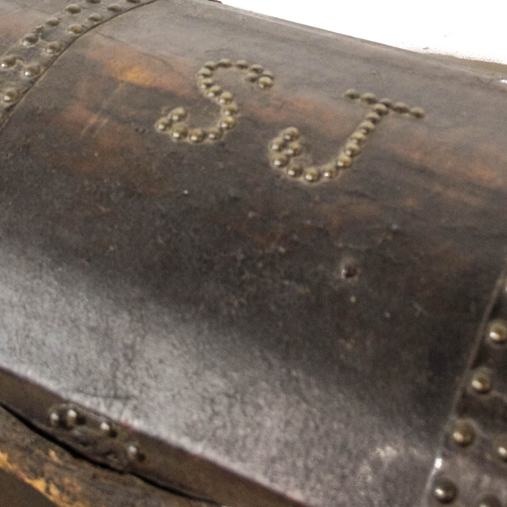 An antique dark brown leather domed trunk decorated with metal studs and initials on the curved lid. View VII