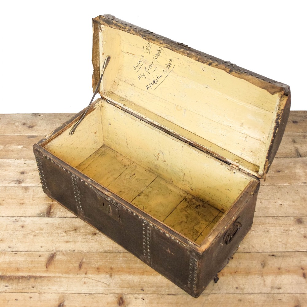 An antique dark brown leather domed trunk decorated with metal studs and initials on the curved lid. View IX