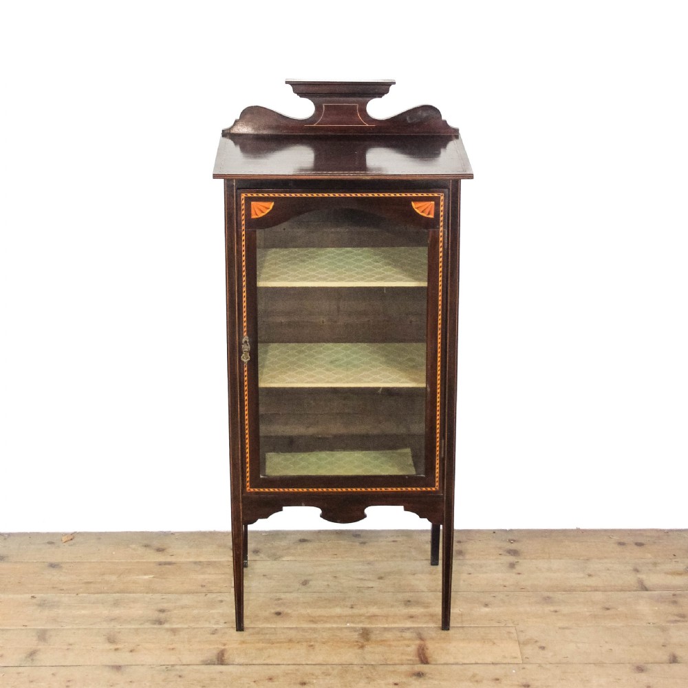 An Edwardian dark mahogany single door display cabinet featuring delicate satinwood inlay, fan corner marquetry, a shaped pediment, and square tapered legs. View II