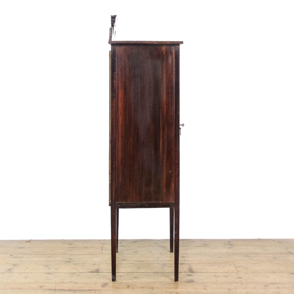 An Edwardian dark mahogany single door display cabinet featuring delicate satinwood inlay, fan corner marquetry, a shaped pediment, and square tapered legs. View VIII